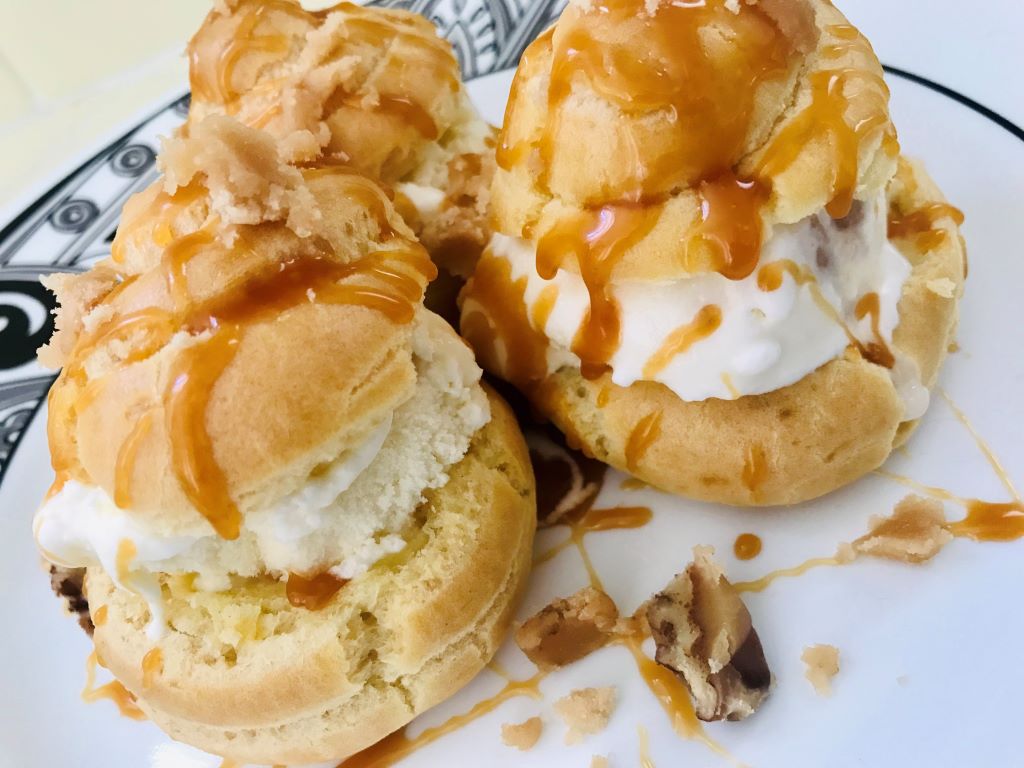 Profiteroles with homemade dulce de leche ice cream, pralines and salted caramel sauce